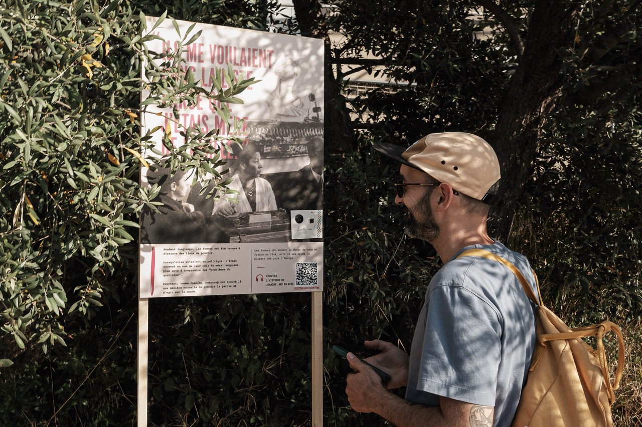 Un visiteur lit un panneau de l'exposition Nos libertés en extérieur